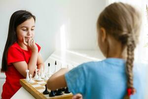 Two cute children playing chess at home photo