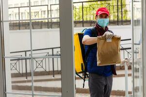 Delivery Man standing with yellow thermo backpack for food delivery near the entrance home with empty space to copy paste photo