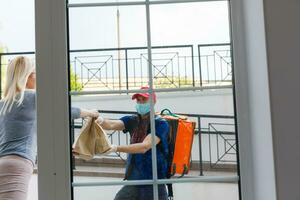 Courier with thermal backpack delivering fresh lunches to a young business woman. Takeaway restaurant food delivery concept photo