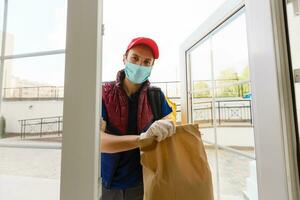 Delivery Man standing with yellow thermo backpack for food delivery near the entrance home with empty space to copy paste photo