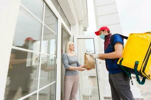 Delivery Man standing with yellow thermo backpack for food delivery near the entrance home with empty space to copy paste photo