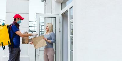 delivery man with thermo backpack and smiling woman in office photo