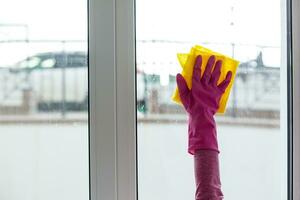 mujer limpieza un ventana con limpieza pulverizador. foto