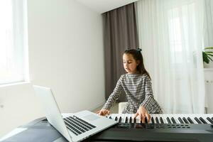 Home lesson on music for the girl on the piano. The idea of activities for the child at home during quarantine. Music concept photo