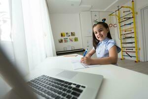 alegremente linda niña niños emocionado utilizando computadora aprendizaje Trabajo escolar. niño disfrutar e-learning en fiesta a hogar. foto