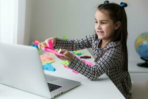 Pretty stylish schoolgirl studying homework math during her online lesson at home, social distance during quarantine, self-isolation, online education concept, home schooler photo