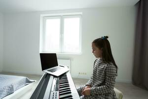 pequeño niña distancia aprendizaje el piano en línea durante cuarentena. coronavirus concepto. foto