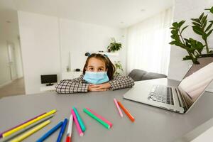 Pretty stylish schoolgirl studying homework math during her online lesson at home, social distance during quarantine, self-isolation, online education concept, home schooler photo