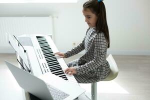 pequeño niña distancia aprendizaje el piano en línea durante cuarentena. coronavirus concepto. foto