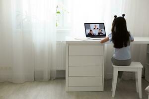 Pretty stylish schoolgirl studying homework math during her online lesson at home, social distance during quarantine, self-isolation, online education concept, home schooler photo