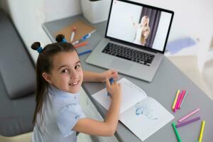 bonito elegante Chica de escuela estudiando deberes matemáticas durante su en línea lección a hogar, social distancia durante cuarentena, autoaislamiento, en línea educación concepto, hogar escolar foto