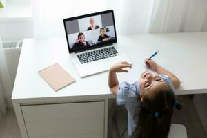 pequeño niña estudiando con ordenador portátil en línea aprendizaje foto