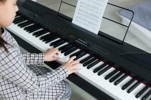 Cute little girl plays on piano, synthesizer. Training. Education. School. Aesthetic training. Elementary classroom. photo