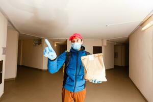 entrega hombre enviar comida bolso a puerta mando para sin contacto o contacto gratis desde entrega jinete en frente casa para social distanciamiento para infección riesgo. foto