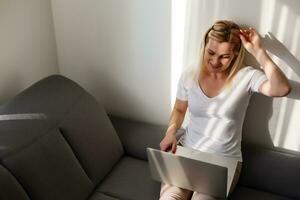 mujer utilizando un ordenador portátil mientras relajante en el sofá foto