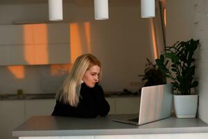 irreconocible mujer trabajando en su computadora desde su hogar oficina frente a el espectacular metropolitano ciudad a amanecer. mujer de negocios haciendo investigación desde un lujo hotel habitación foto