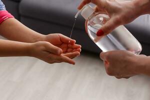 Close up mother applies disinfectant to her daughter to prevent infection. Family hygiene concept. photo