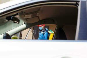 comida entrega hombre en un protector máscara y guantes con un termo mochila cerca un coche durante el cuarentena período foto