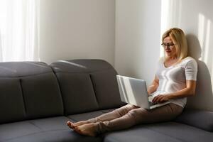 A smiling woman in front of her laptop at home photo