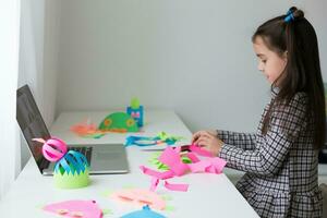 Beautiful little girl cutting paper with scissors on the art lesson class. Children education concept. Kids crafts.Back to schoo photo