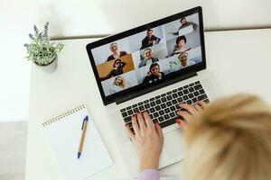 Back view of female employee speak talk on video call with diverse multiracial colleagues on online briefing, woman worker have Webcam group conference with coworkers on modern laptop at home photo