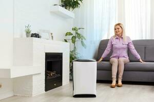 Air purifier in a living room, woman working with laptop with filter for clean room photo