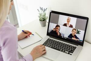 Cropped image of young female student attending online lecture on laptop at desk photo