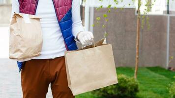 mensajero en protector máscara y médico guantes entrega para llevar alimento. entrega Servicio debajo cuarentena, enfermedad brote, coronavirus covid-19 pandemia condiciones. foto