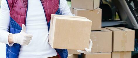 Courier, delivery man in medical latex gloves and mask safely delivers online purchases in white box to the door during the coronavirus epidemic, COVID-19. Stay home, safe concept. photo