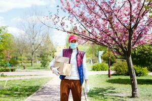 Man with face mask is delivering food and groceries during virus epidemic. photo