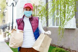 hombre con cara máscara es entregando comida y comestibles durante virus epidemia. foto