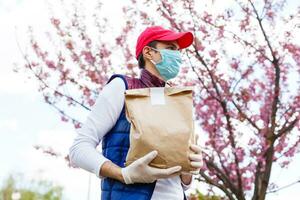 tienda de comestibles entrega hombre vistiendo médico guantes y cara mascarilla. en línea compras y entrega para comestibles, vino y alimento. yo cuarentena durante coronavirus pandemia. comida entrega Servicio mensajero foto