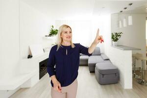 Smart house. Nice joyful woman looking at the sensory panel while pressing it photo