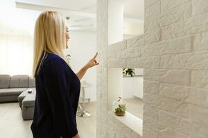 Smart house. Nice joyful woman looking at the sensory panel while pressing it photo