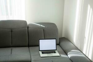 Open laptop on the couch. Modern comfortable workplace, distance work. Empty place for text, copy space. photo