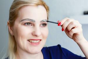 woman paints eyebrows at home closeup photo