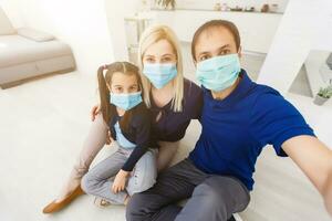 Three people Caucasian family with dad, mom and daughter staying at home wearing facial masks, portrait photo