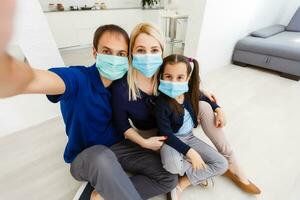 Three people Caucasian family with dad, mom and daughter staying at home wearing facial masks, portrait photo