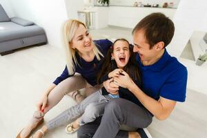 smiling parents tickling preteen daughter in bed photo