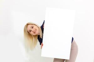 Girl and blank canvas. Copy space on canvas board for image or message. Young woman looking at mockup poster and standing over grey background. photo