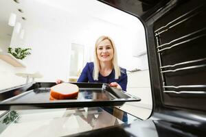 retrato de un joven mujer preparando comida en el cocina. joven ama de casa es participación recién horneado carne foto