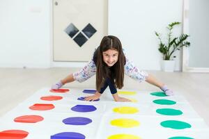 little girl playing on a twister game at home. Girl smiles and looks up photo