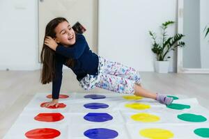 little girl playing on a twister game at home. Girl smiles and looks up photo