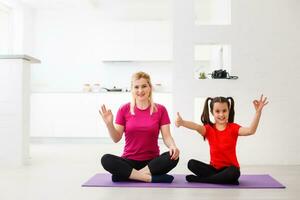 Mother and daughter doing yoga exercises on mat at home. photo