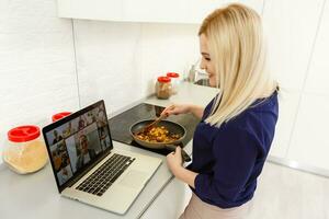 Young beautiful woman with laptop in the kitchen, looking for recipe photo