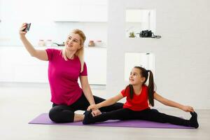 Mother and daughter doing yoga exercises on mat at home. photo