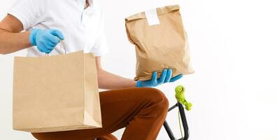 un hombre en protector máscara es entregando comida en un bicicleta. en línea compras y Rápido entrega . cuarentena foto