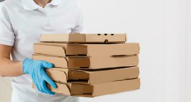 hombre desde entrega Servicio en camiseta, en protector máscara y guantes dando comida orden y participación Pizza cajas terminado blanco antecedentes foto