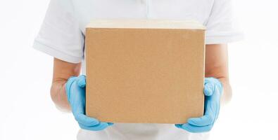 home delivery, online order. A man in uniform, a medical mask and rubber gloves with a box, a parcel in his hands. Food and food delivery during the quarantine of the coronavirus pandemic photo