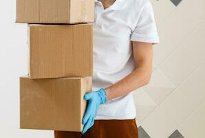 Delivery man holding cardboard boxes in medical rubber gloves and mask. copy space. Fast and free Delivery transport . Online shopping and Express delivery . Quarantine photo